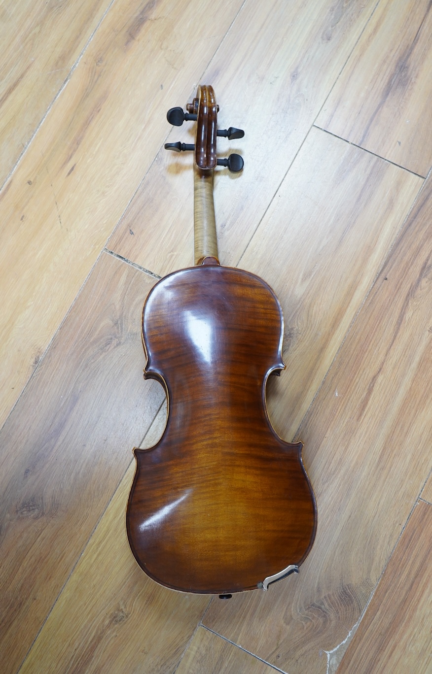 An early 20th century German violin, with a label reading ‘Copy of Joseph Guarnerius, Made in Germany’, body length 35.5cm, cased with a bow by Tourte. Condition - good.